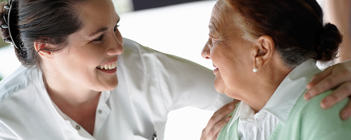 Health care personnel holding her arms around an elderly woman